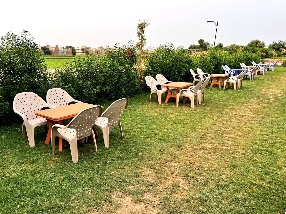 Comfortable lawn seating with tables and hedges, fields behind